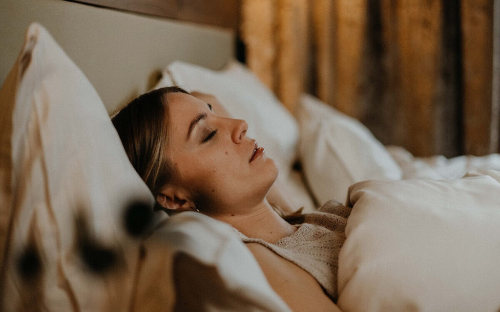 Epigenetisch wirksame Abendroutine im Ayurveda Frau liegt schlafend in einem Bett