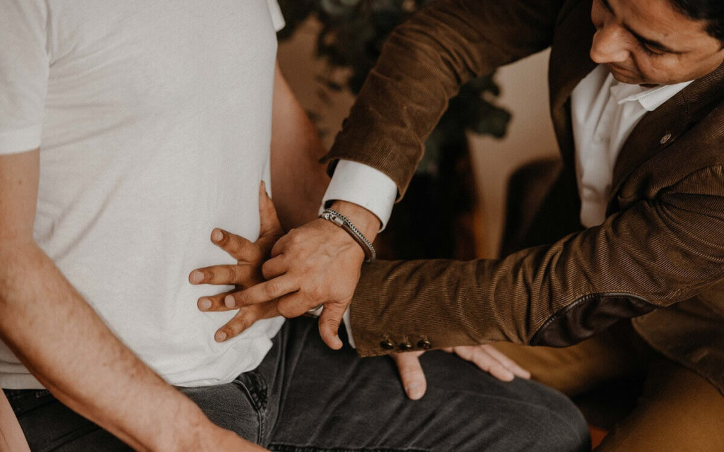 Mann untersucht mit seiner Hand den Bauch eines zweiten Mannes